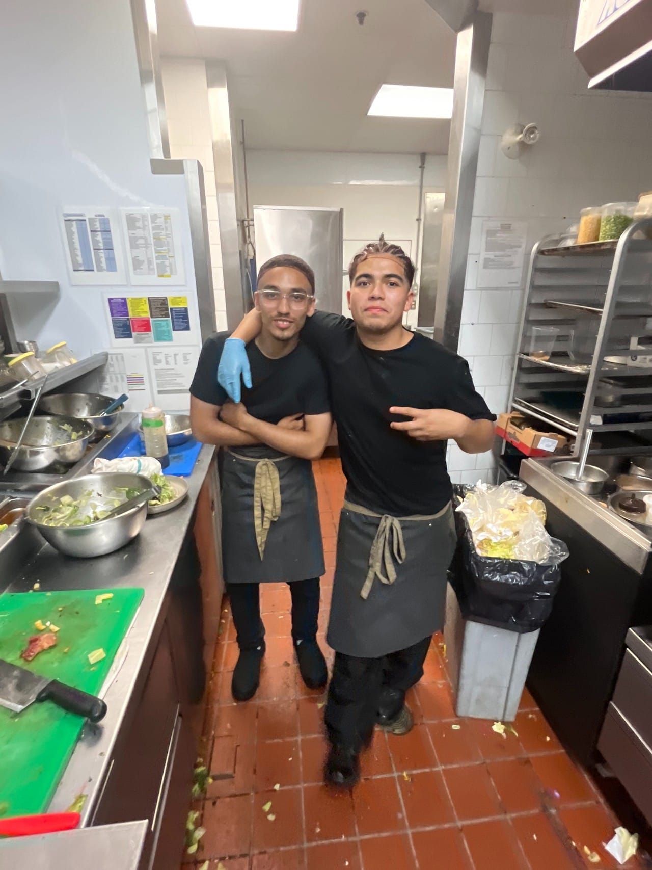 Deux cuisiniers en tablier noir posent ensemble dans la cuisine du restaurant
